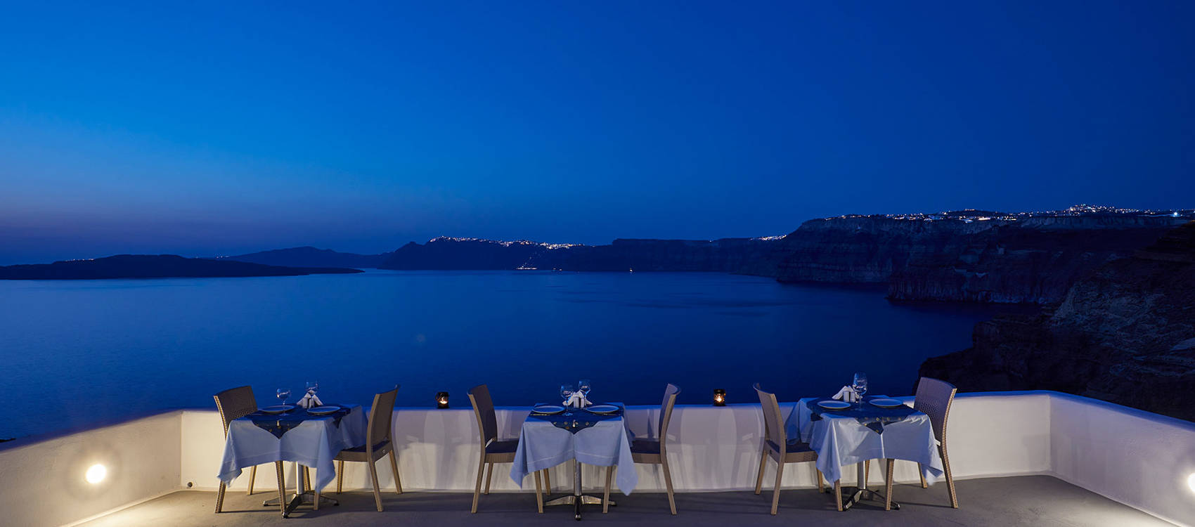 
Santorini View Hotel restaurant terrace with table seats and caldera view, at evening