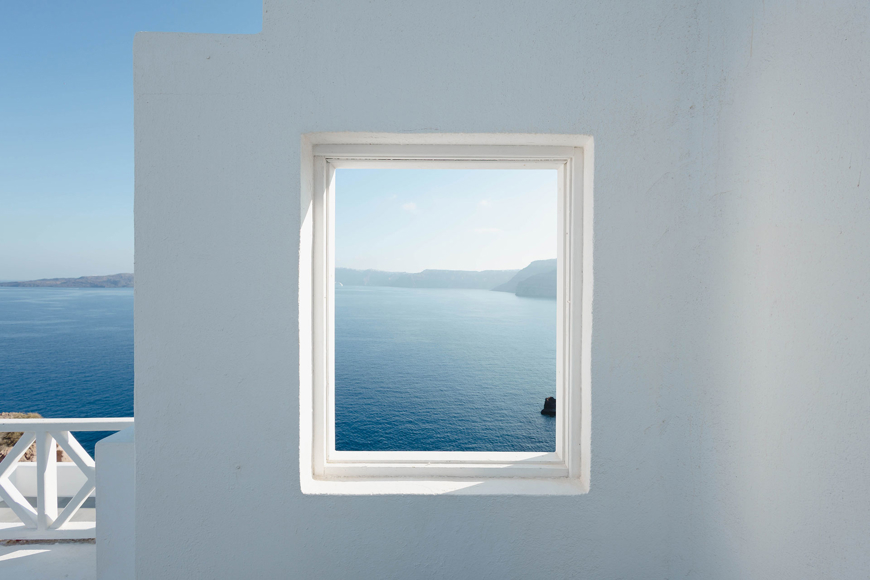 Framed view of the caldera through a white architectural window in Santorini View Hotel overlooking the sea