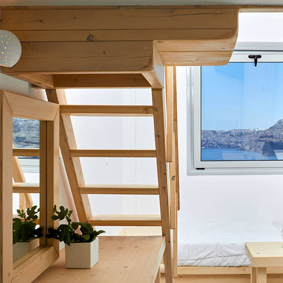 Cozy Junior Suite at Santorini View Hotel with wooden loft staircase, sea view window, and natural decor