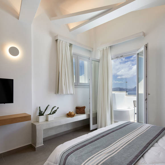 Bright bedroom of Deluxe double room with modern decor, white curtains and balcony with sea view