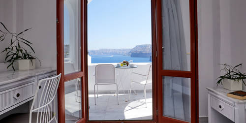 
Santorini View Hotel brown doors to a balcony with white table seats and sea view