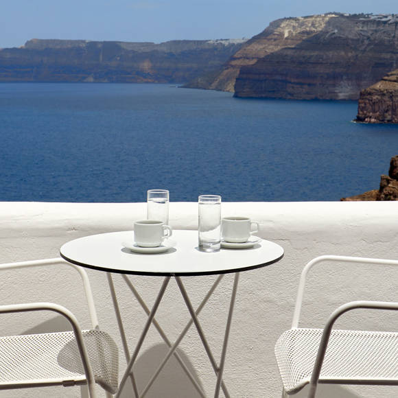Balcony of the Superior Double room table with coffee cups overlooking the Aegean Sea and Santorini caldera cliffs