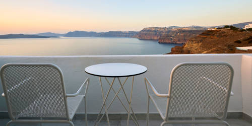 
Santorini View Hotel balcony in white colors and sunset view at the aegean sea