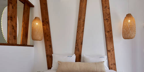 
Santorini View Hotel double bed with white and beige linen, and bamboo ceiling lamps