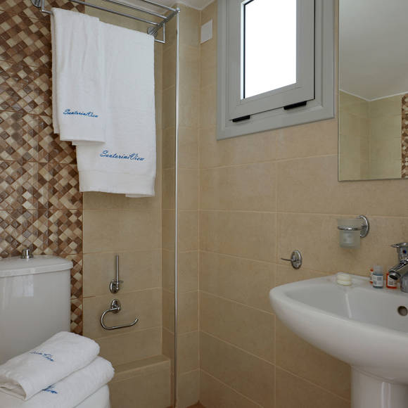 Bathroom of the Junior Suite at Santorini View Hotel featuring beige tiles, mirror, and plush towels