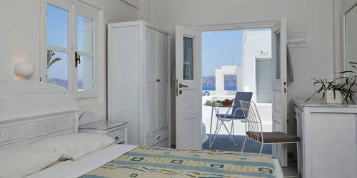 
Santorini View Hotel room with double bed, desk and mirror, and terrace with table seats for breakfast