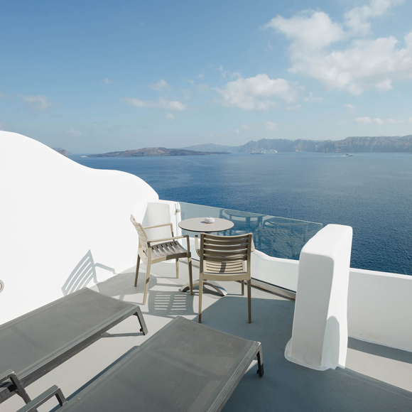 Private terrace of Deluxe double room with sunbeds and table offering panoramic views of the Aegean sea 