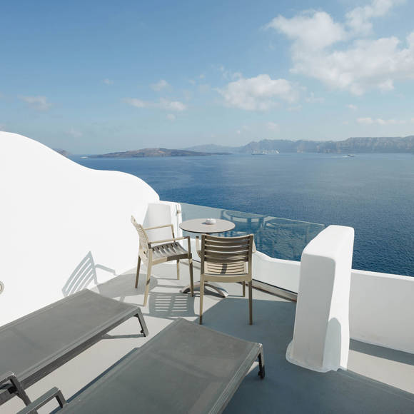 Private terrace of Deluxe double room with sunbeds and table offering panoramic views of the Aegean sea 