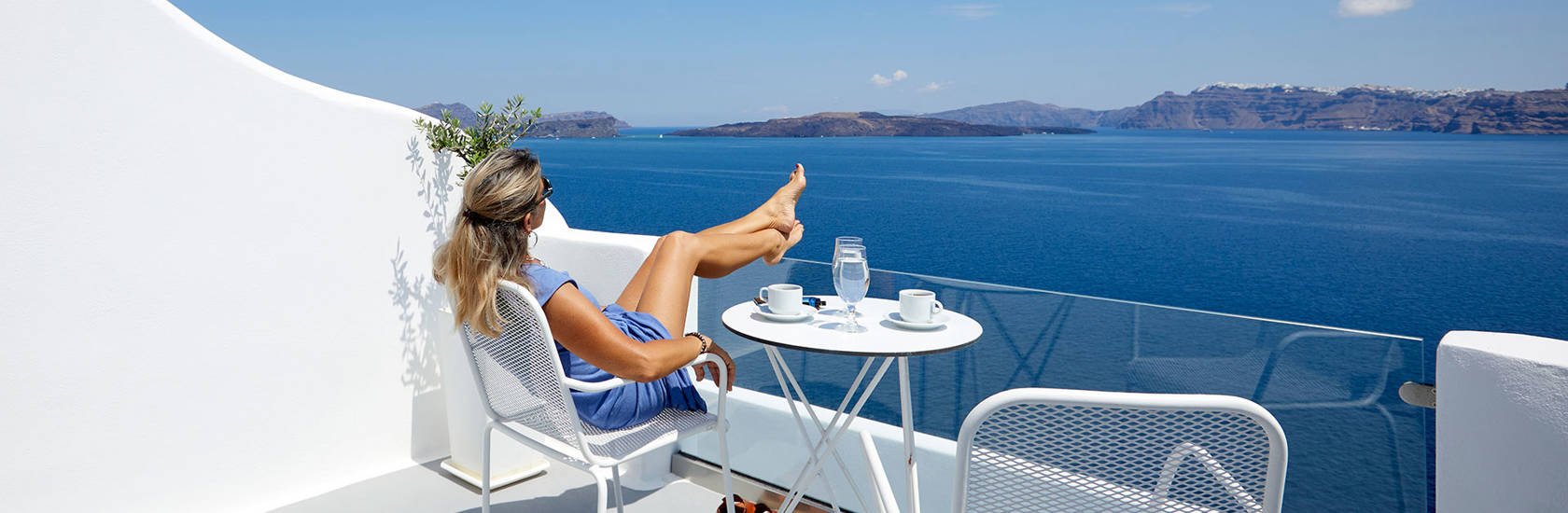 
Santorini View Hotel woman seating at a balcony looking at the caldera and  sea view