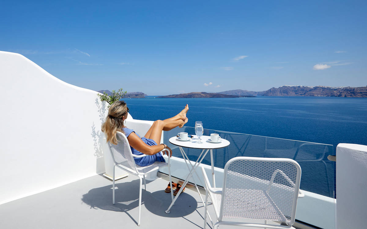 
Santorini View Hotel woman seating at a balcony looking at the caldera and  sea view