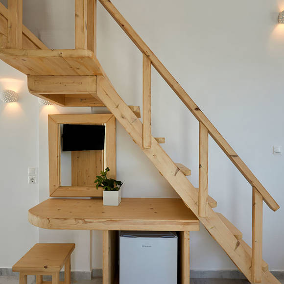 Charming Junior Suite at Santorini View Hotel with wooden staircase, mini fridge, mirror, and natural modern decor