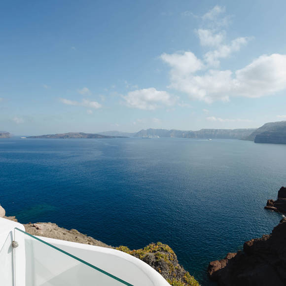 Breathtaking caldera view from a cliffside terrace of Deluxe double room overlooking the deep blue Aegean sea