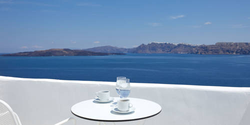 
Santorini View Hotel white table seats, greek coffee and glasses of water, at a balcony with caldera sea view