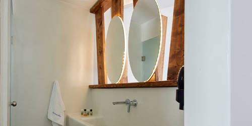 
Santorini View Hotel bathroom with two mirrors and wooden decoration