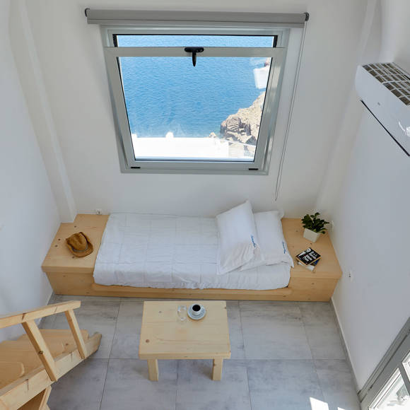 Bright Junior Suite at Santorini View Hotel with modern wooden design, sea view window and seating area