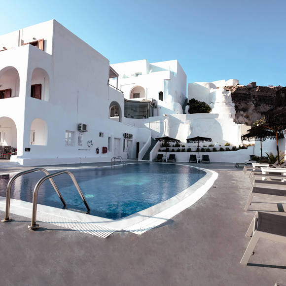Outdoor swimming pool of Santorini View Hotel surrounded by sun loungers and white Cycladic architecture 