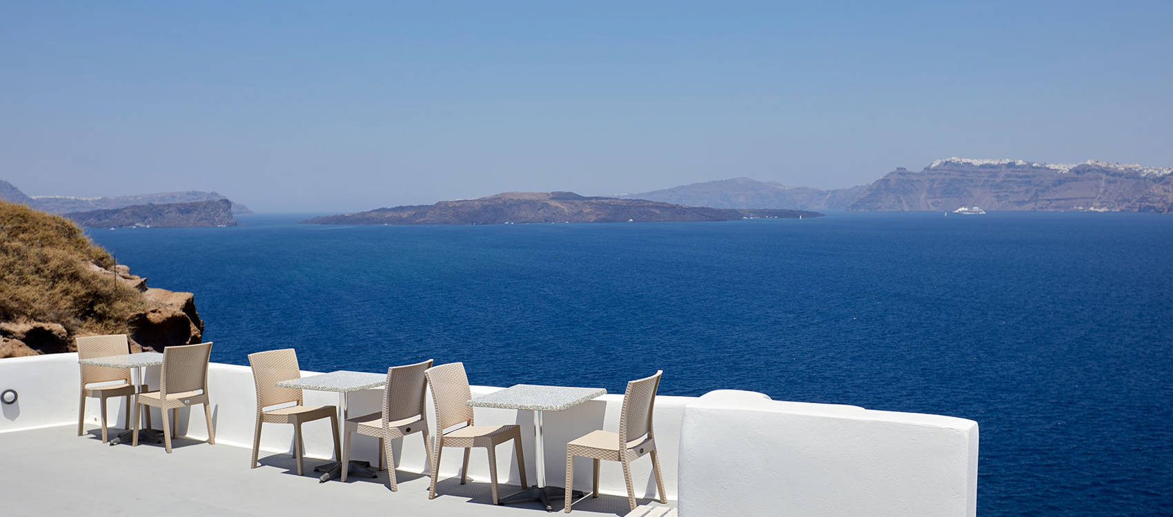 
Βεράντα εστιατορίου Santorini View Hotel με τραπεζοκαθίσματα, θέα στην καλντέρα και γαλάζιο ουρανό