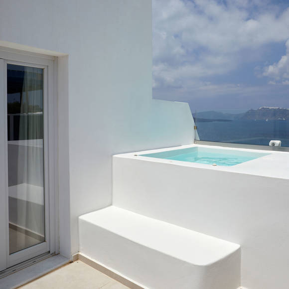 Private terrace of Deluxe double room with built-in hot tub and panoramic caldera view under the bright Santorini sky
