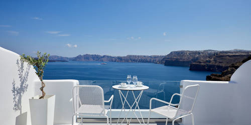 
Santorini View Hotel balcony in white colors with furniture and view at the aegean sea and caldera