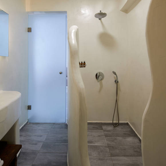 Modern bathroom in the Suite at Santorini View Hotel featuring a walk-in shower and smooth sculpted walls