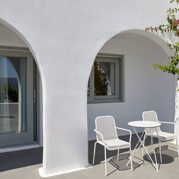 Suite patio at Santorini View Hotel with white arches, minimalist outdoor furniture, and a touch of greenery