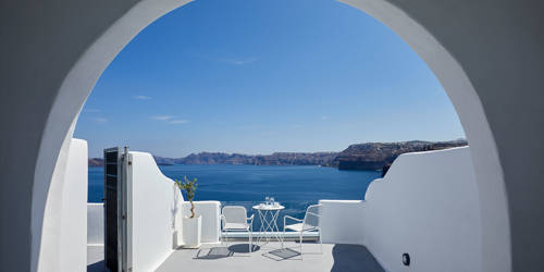 
Santorini View Hotel big balcony in white colors with furniture and view at the aegean sea and caldera