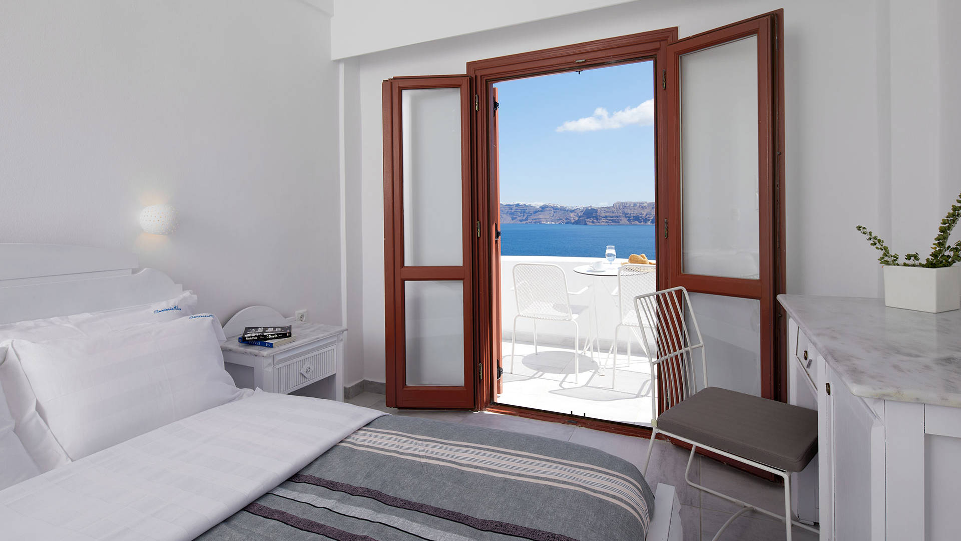 
Santorini View Hotel king size bed and balcony with sea view and white table seats