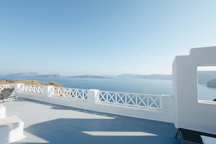 Panoramic terrace with white railing overlooking the deep blue caldera and Aegean sea in Santorini View Hotel