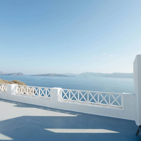 Panoramic terrace with white railing overlooking the deep blue caldera and Aegean sea in Santorini View Hotel