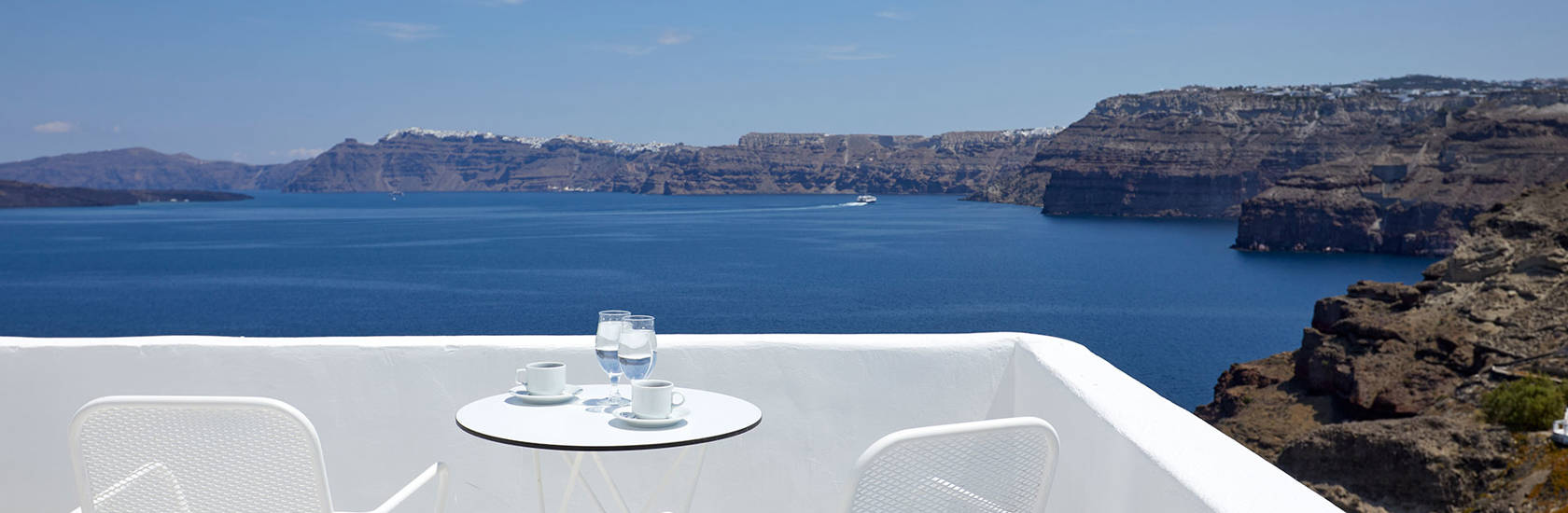 
Santorini View Hotel balcony in white colors, white table seats and caldera view
