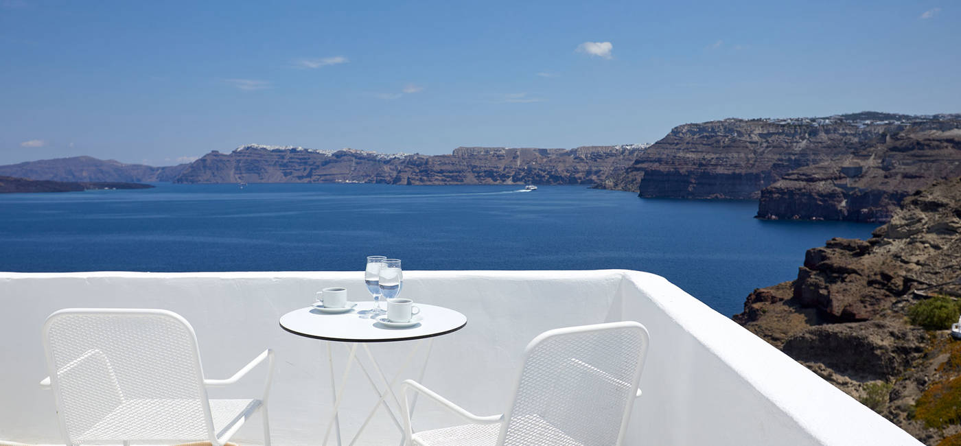 
Santorini View Hotel μπαλκόνι σε λευκά χρώματα, λευκά τραπεζοκαθίσματα και θέα στην καλντέρα