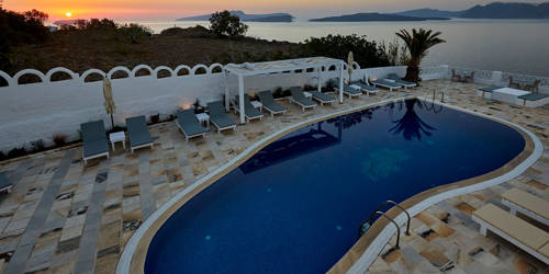 
Santorini View Hotel swimming pool with sunbeds at sunset time