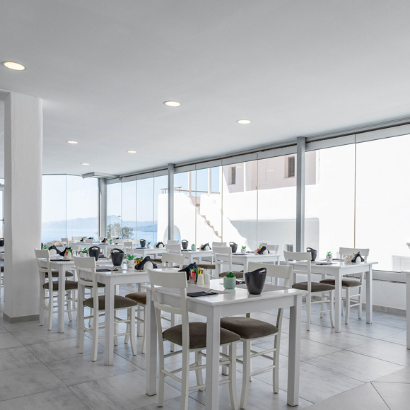 Modern Santorini View Hotel restaurant with white tables, large windows, and sea view