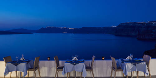 
Santorini View Hotel restaurant terrace with table seats and caldera view, at evening