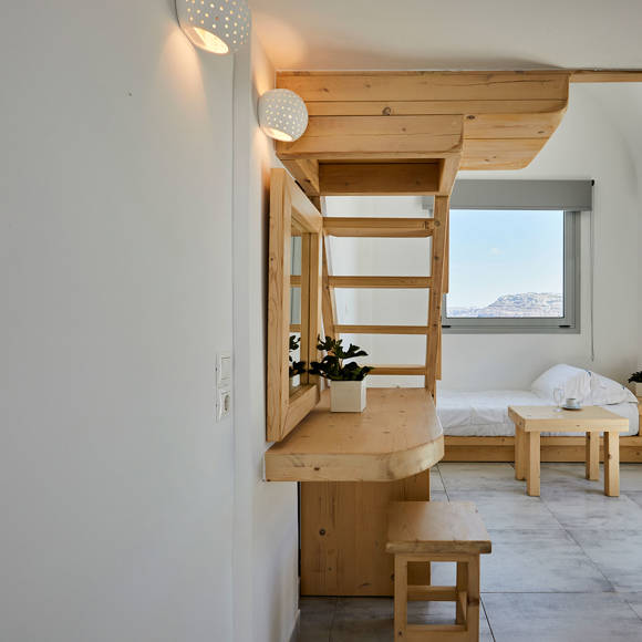 Elegant Junior Suite at Santorini View Hotel with wooden loft, cozy sitting area, and large window with caldera view