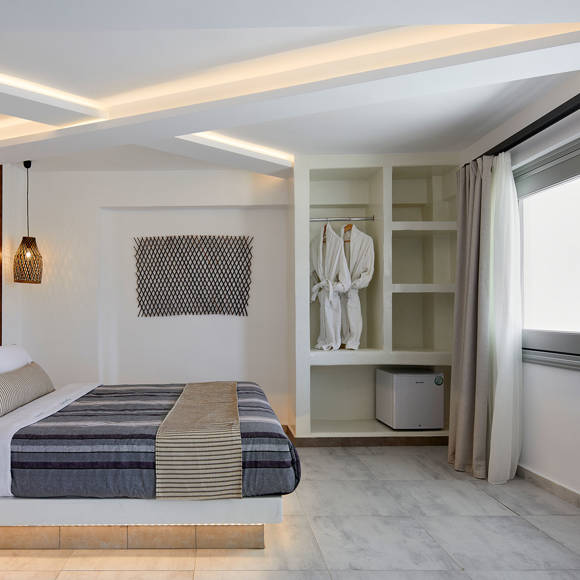 Bright Suite at Santorini View Hotel featuring a modern bedroom with king-size bed, and open wardrobe with robes