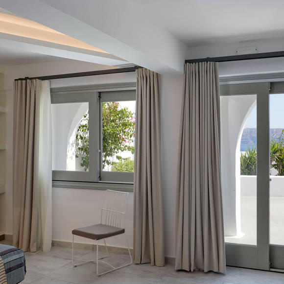 Bright Suite at Santorini View Hotel with elegant windows and doors opening to a terrace with caldera sea view