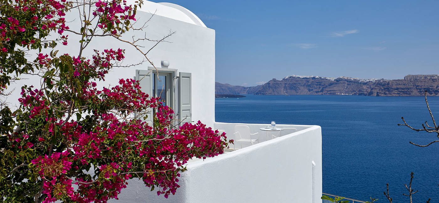 
Santorini View Hotel room with caldera sea view and white balcony with fuchsia bougainvillea undeer the blue sky