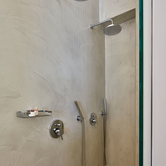 Modern bathroom of Deluxe double room with twin rainfall showers and sleek chrome fixtures against textured walls