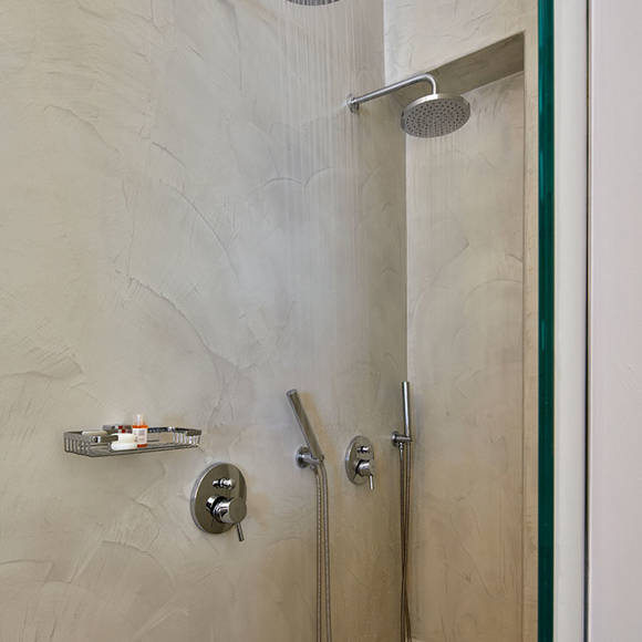 Modern bathroom of Deluxe double room with twin rainfall showers and sleek chrome fixtures against textured walls